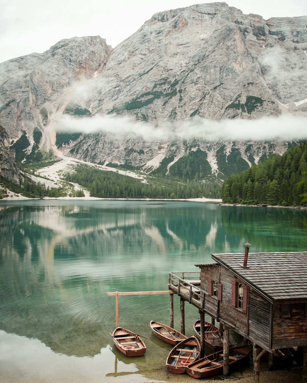 boats under wooden house near mountain