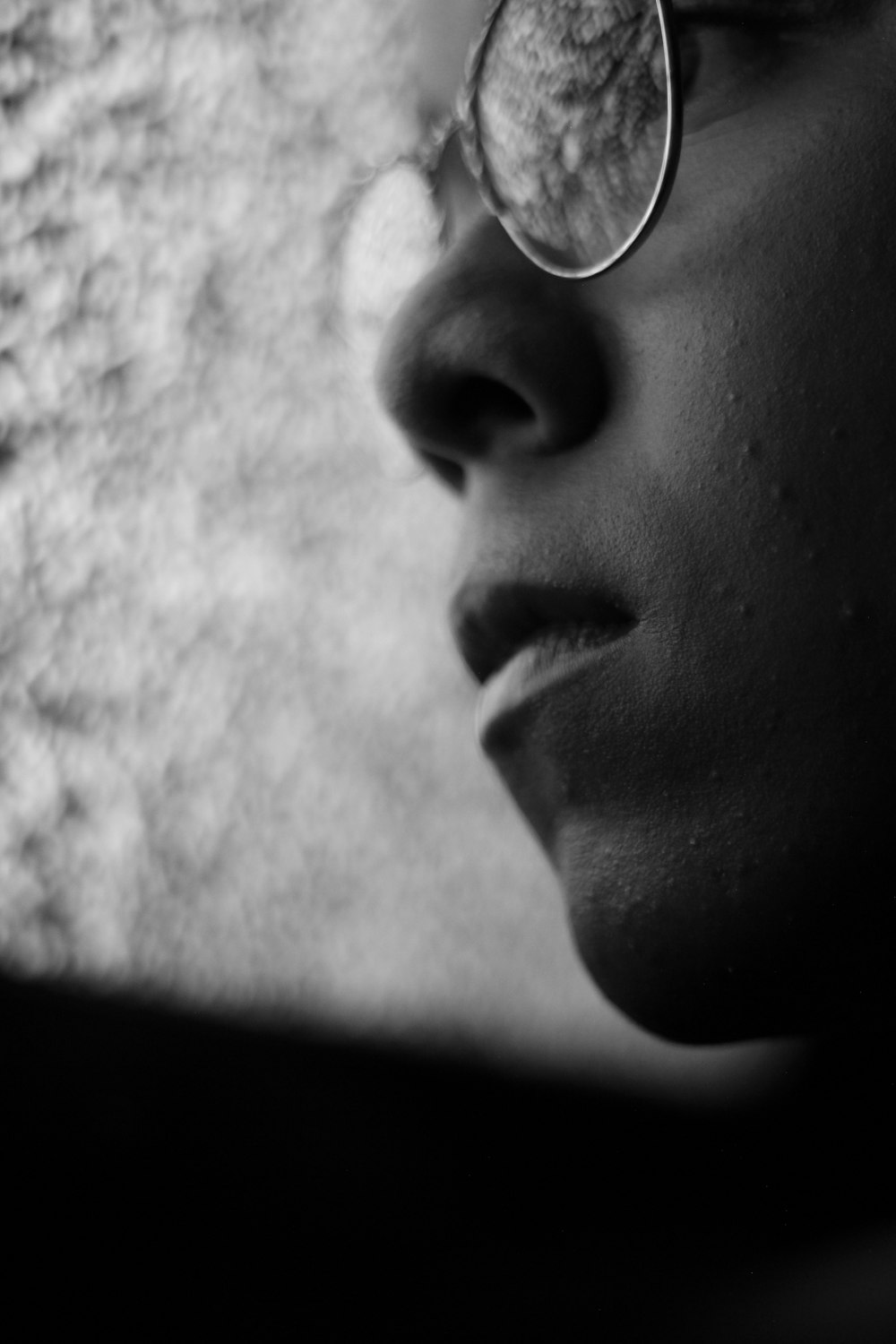 Foto en escala de grises de una persona con anteojos mirando al vidrio