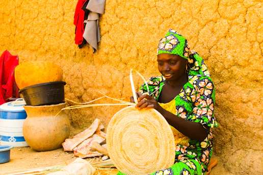 A local artisan teaching a group of women how to weave baskets in a bright workshop.