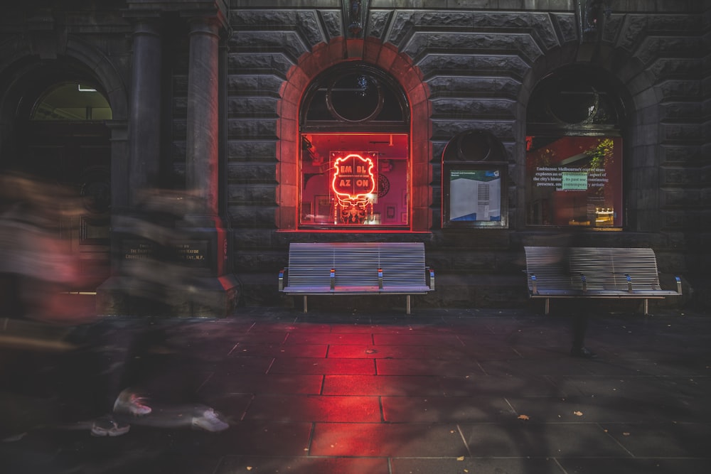 two white benches near red neon signage