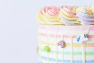 A pastel-colored ice cream cake being carefully decorated with fresh fruits and delicate toppings in a cozy kitchen setting.