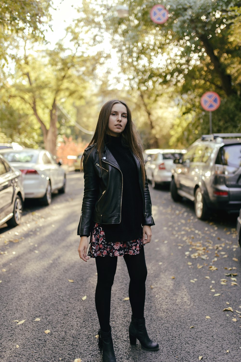 woman standing on road near cars and trees