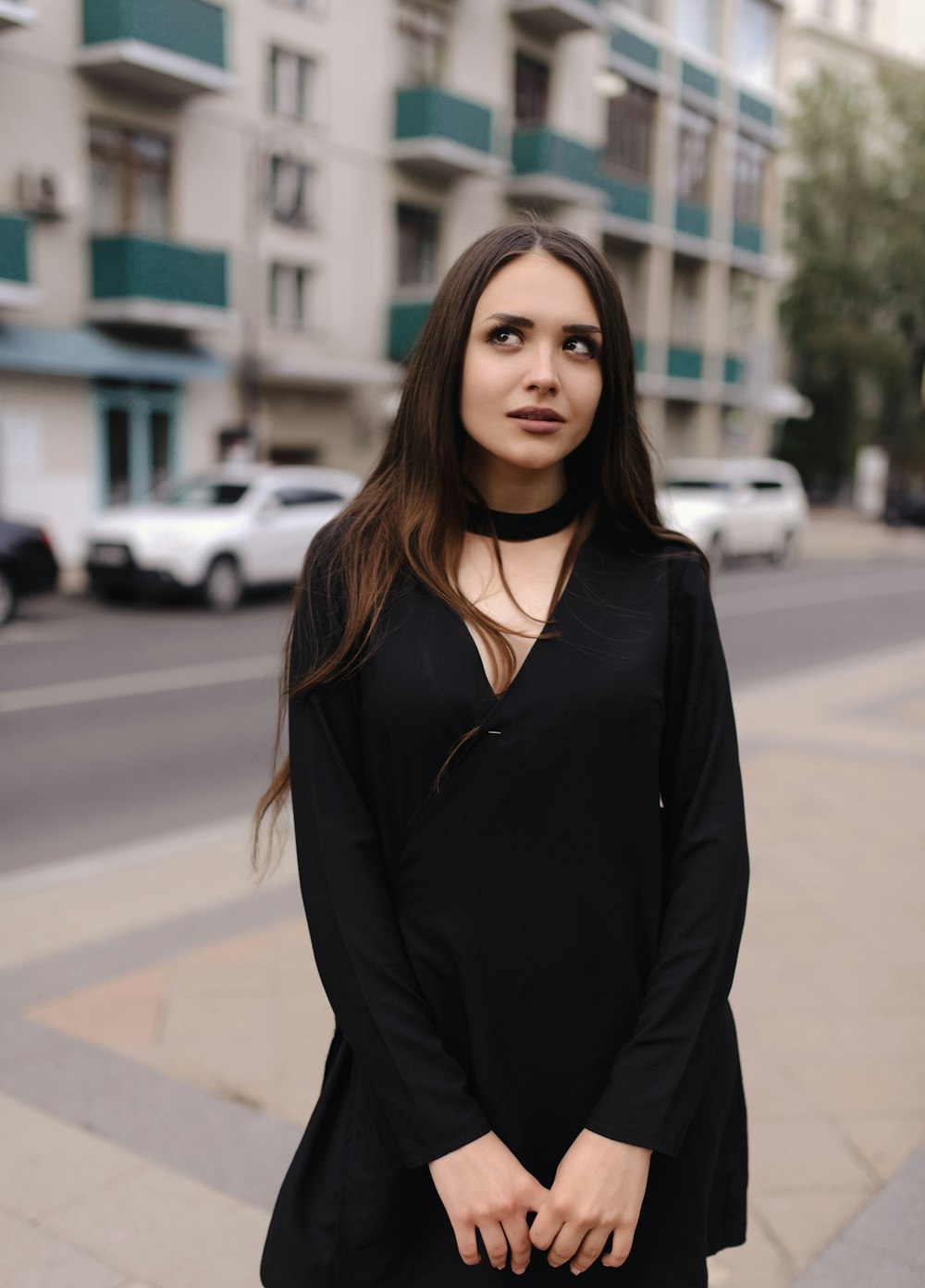 a woman standing on a sidewalk in a black dress