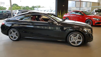 A sleek classic coupe displayed inside a modern luxury garage with ambient lighting.