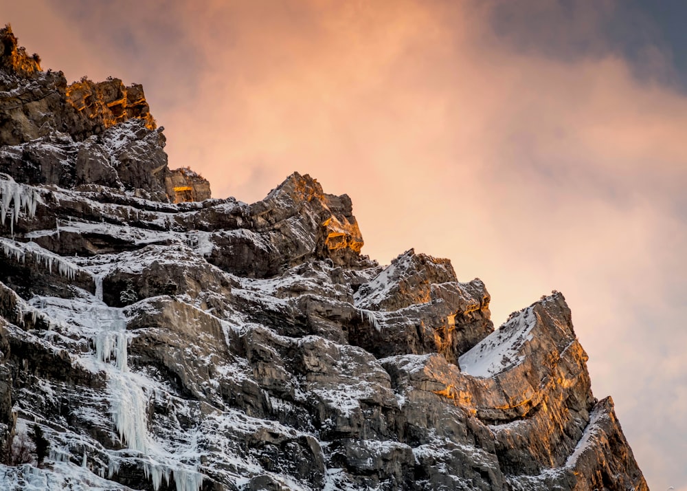 a mountain covered in ice and icicles under a cloudy sky