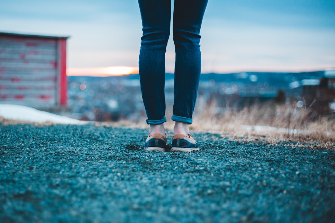 woman in blue denim jeans standing on green field