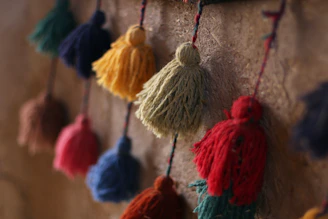 Close-up of colorful tassels and decorative trims arranged artistically on a wooden table.