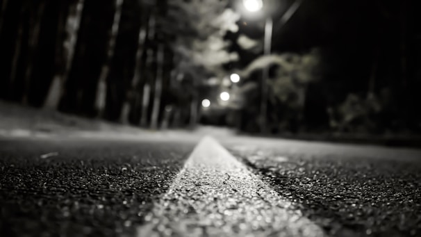 Evening view of a completed asphalt road glistening under streetlights.