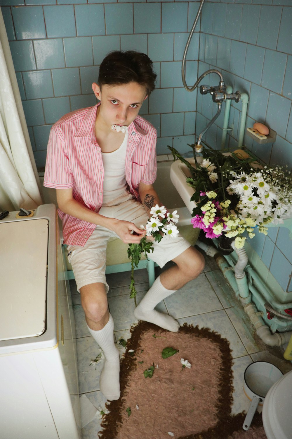man sitting on bath tub holding white flower