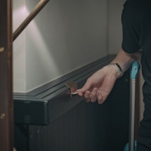 A professional locksmith working on a door lock late at night with a flashlight.