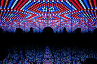 A visually striking play of vibrant LED lights forming geometric patterns in red, blue, and white, creating a tunnel-like illusion with repetitive reflections.
