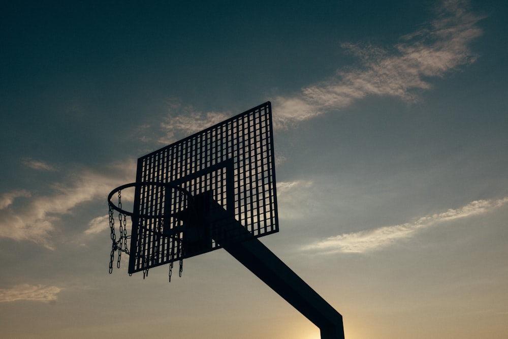 um aro de basquete com o sol se pondo ao fundo