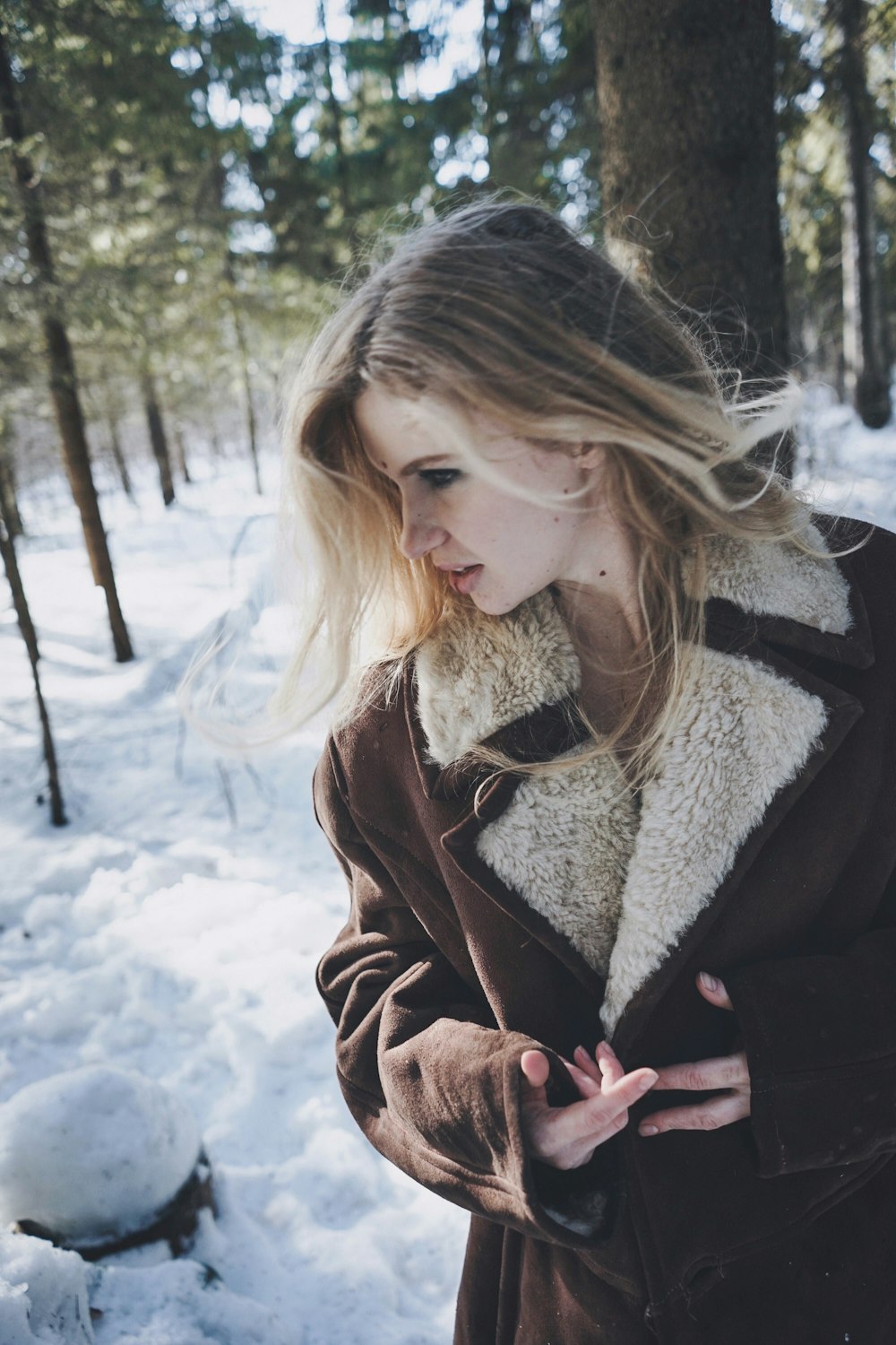 woman standing beside trees with snow