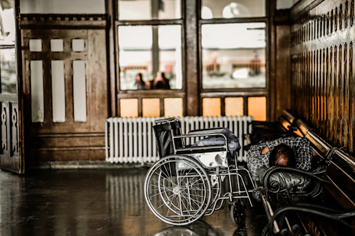gray wheelchair beside person sleeping on bench