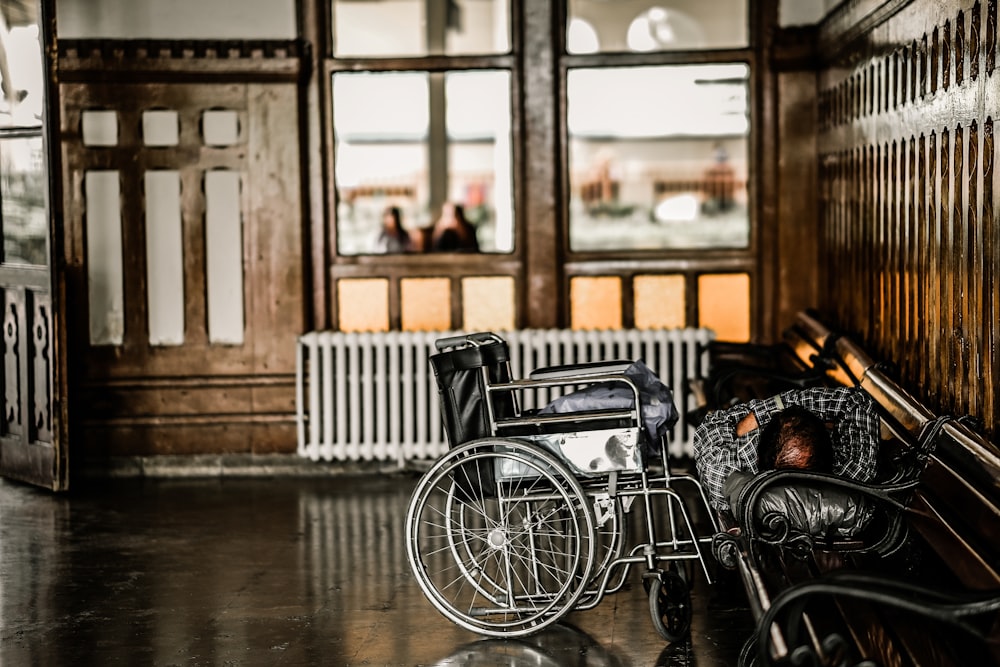 gray wheelchair beside person sleeping on bench