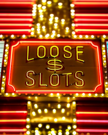 Bright neon lights display the words 'Loose Slots' with a dollar sign in the center. The sign is outlined with bulbs, creating a vibrant and flashy effect typical of a casino or entertainment venue.