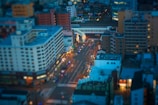 A dramatic drone shot over a bustling cityscape at twilight, highlighting architectural lines and glowing lights.