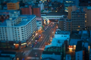 A dramatic drone shot over a bustling cityscape at twilight, highlighting architectural lines and glowing lights.