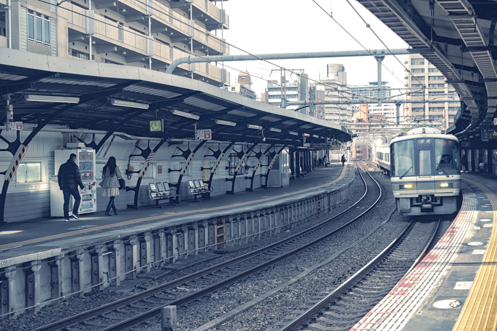 uomo e donna che camminano sul capannone d'attesa del treno