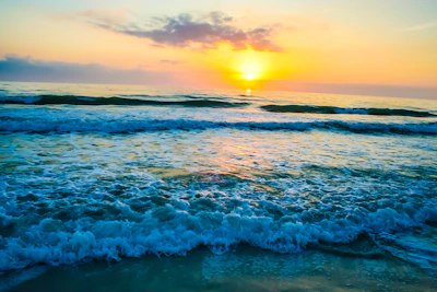 A stunning sea view from a hotel balcony overlooking calm waves and a colorful sunset.