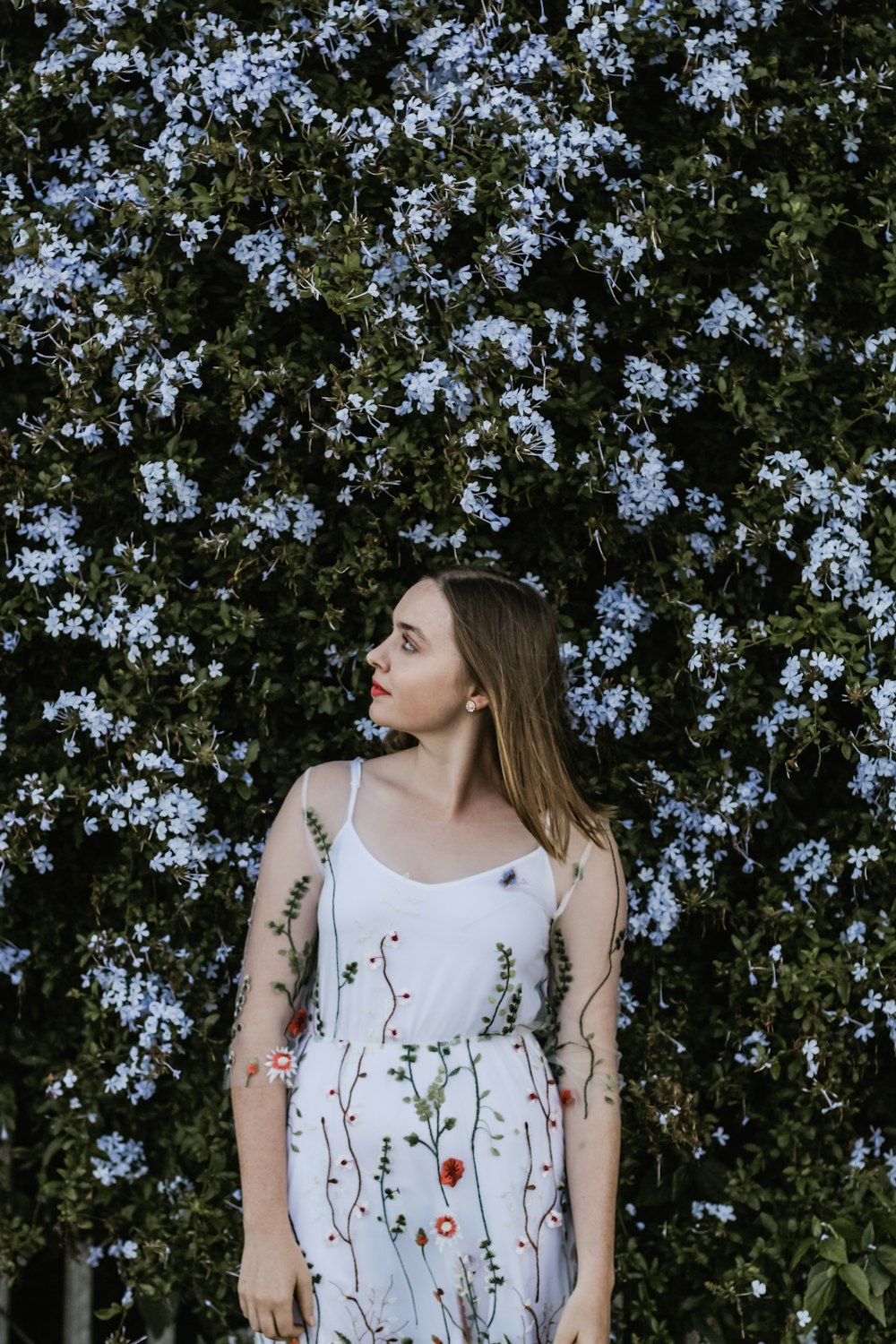 woman standing beside white-petaled flower