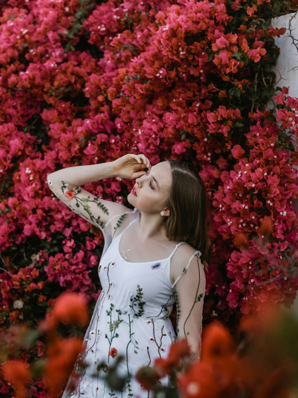 woman in white dress behind red flowers