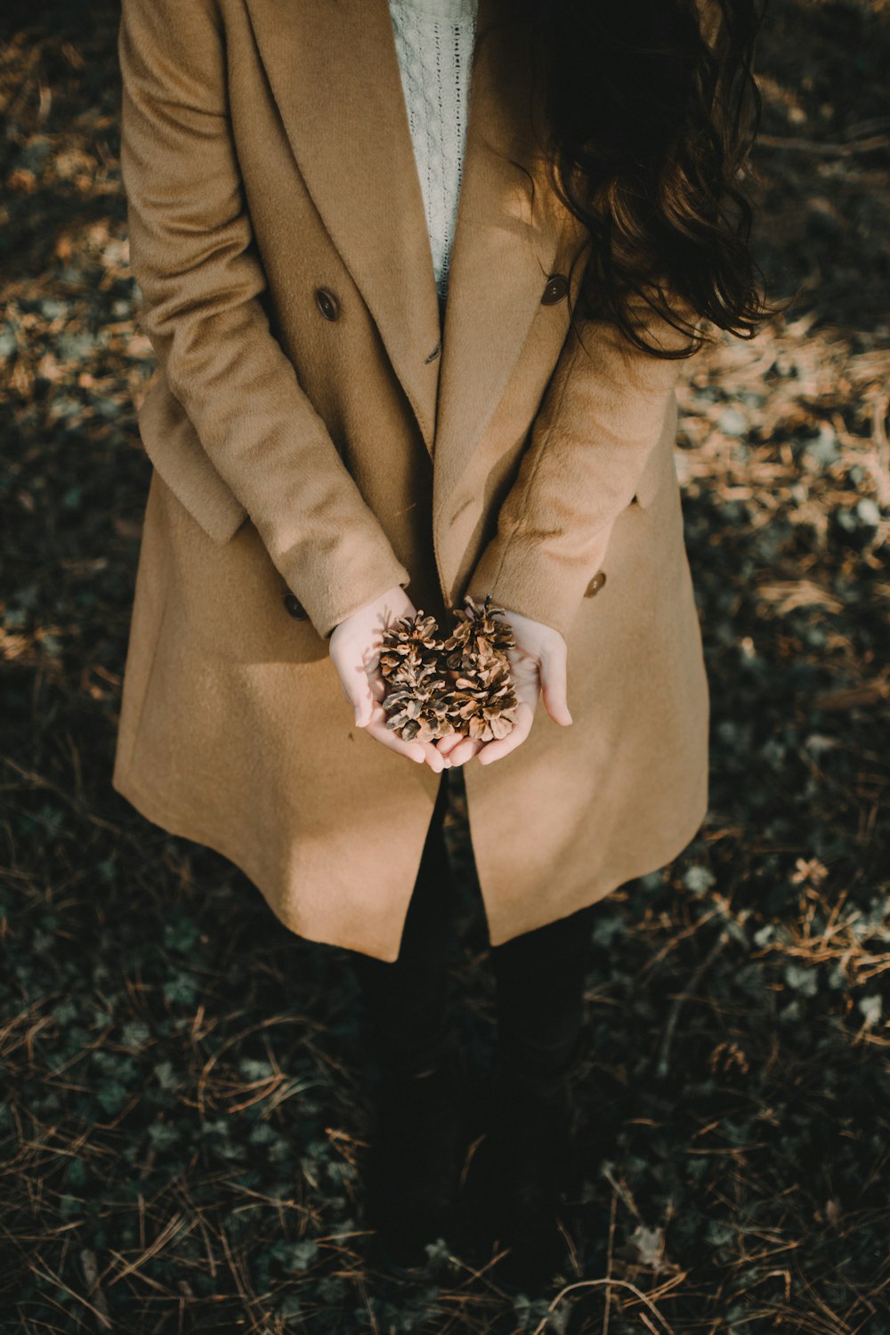 femme portant un blazer marron tenant une feuille séchée
