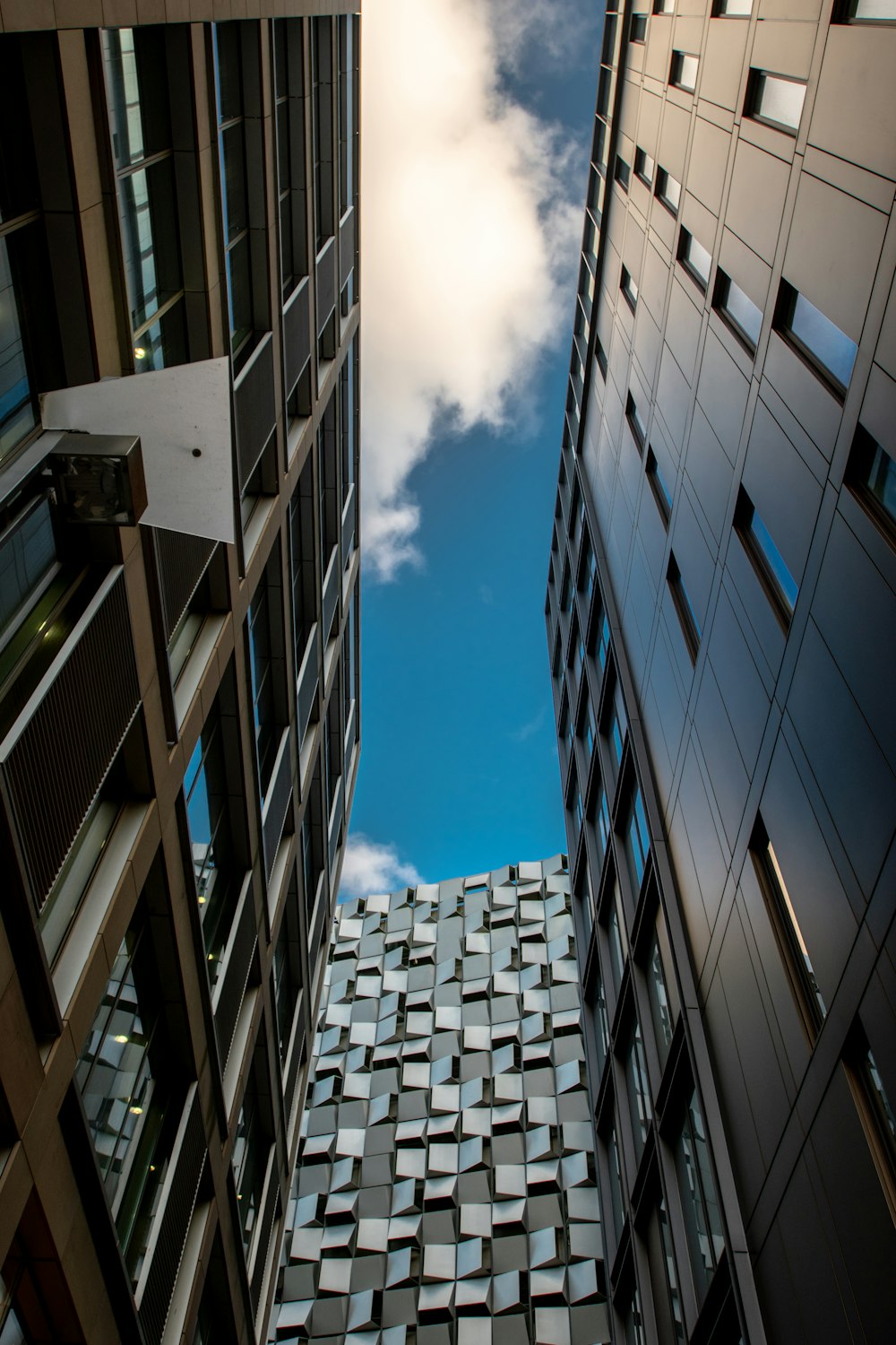 shallow focus photography of three buildings under white clouds at daytime