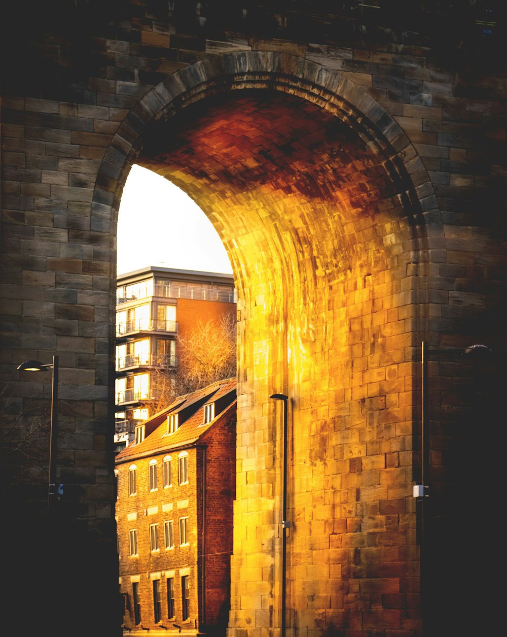 an arch in a brick wall with a building in the background