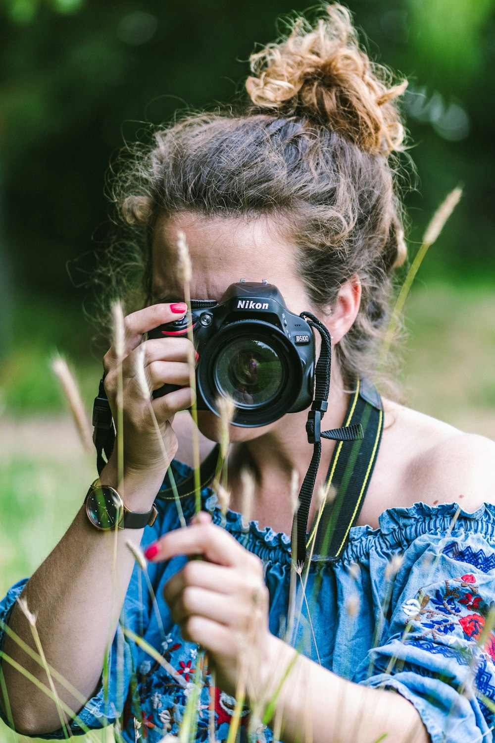 woman wearing blue dress holding camera during daytime