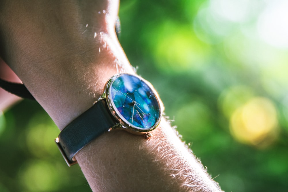 round blue analog watch with black leather strap