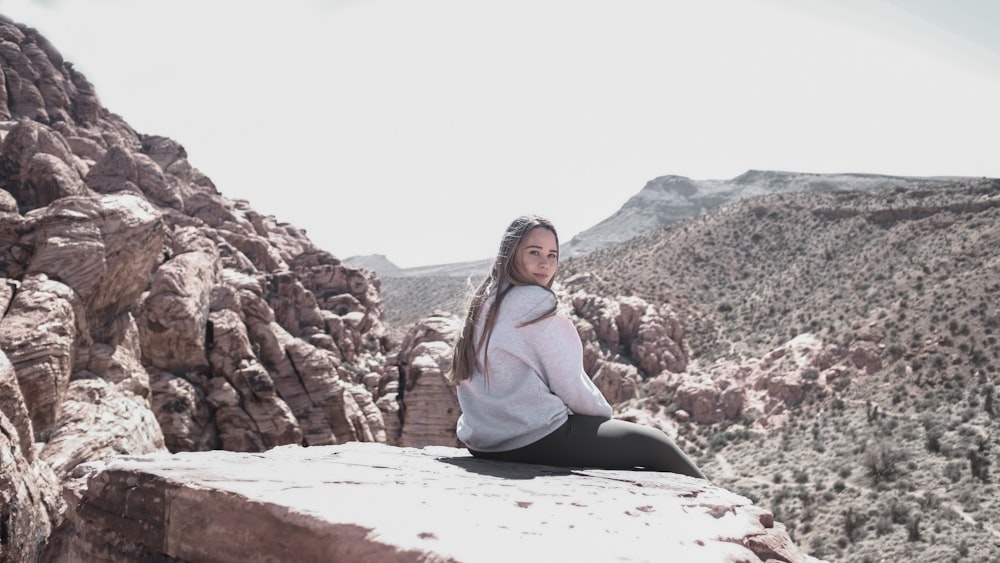 woman sitting on mountain cliff