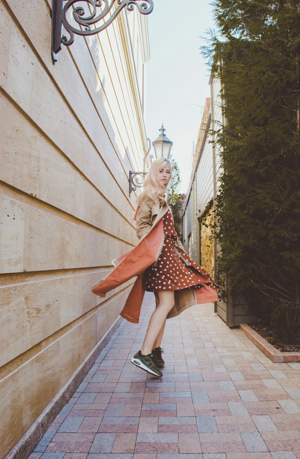 woman in maroon and white polka-dot dress standing at alley