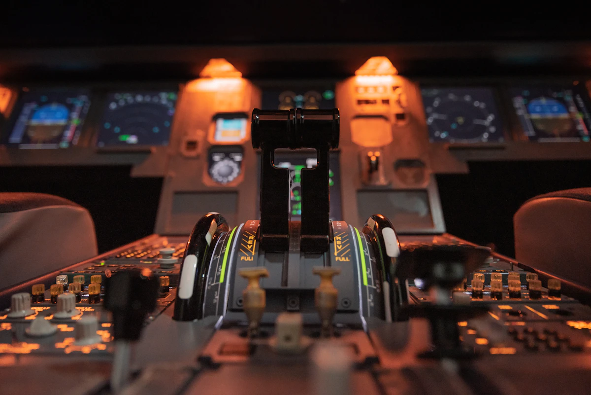 Throttle levers in an airplane cockpit lit by warm instrument lights