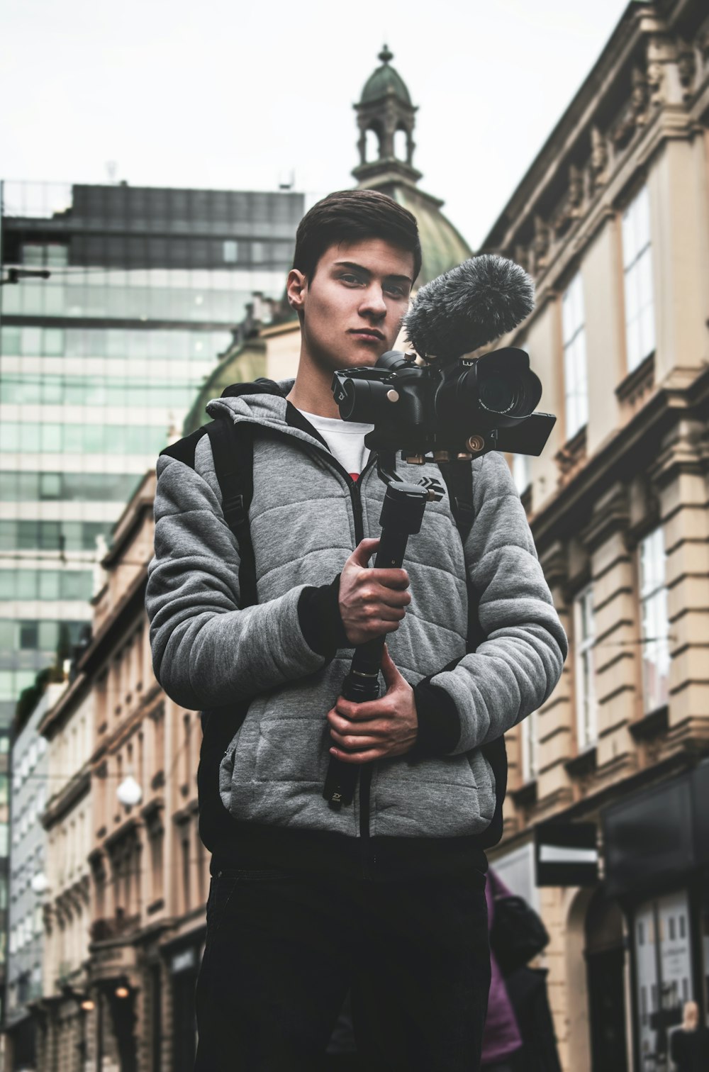 standing man holding camera near buildings