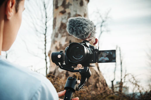 person talking video of himself near tree during daytime