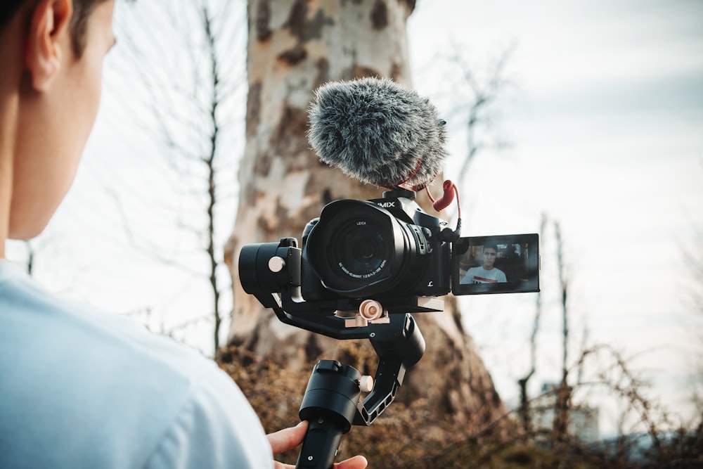 person talking video of himself near tree during daytime