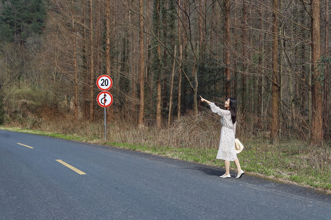 woman near 20 road signage surrounded by trees