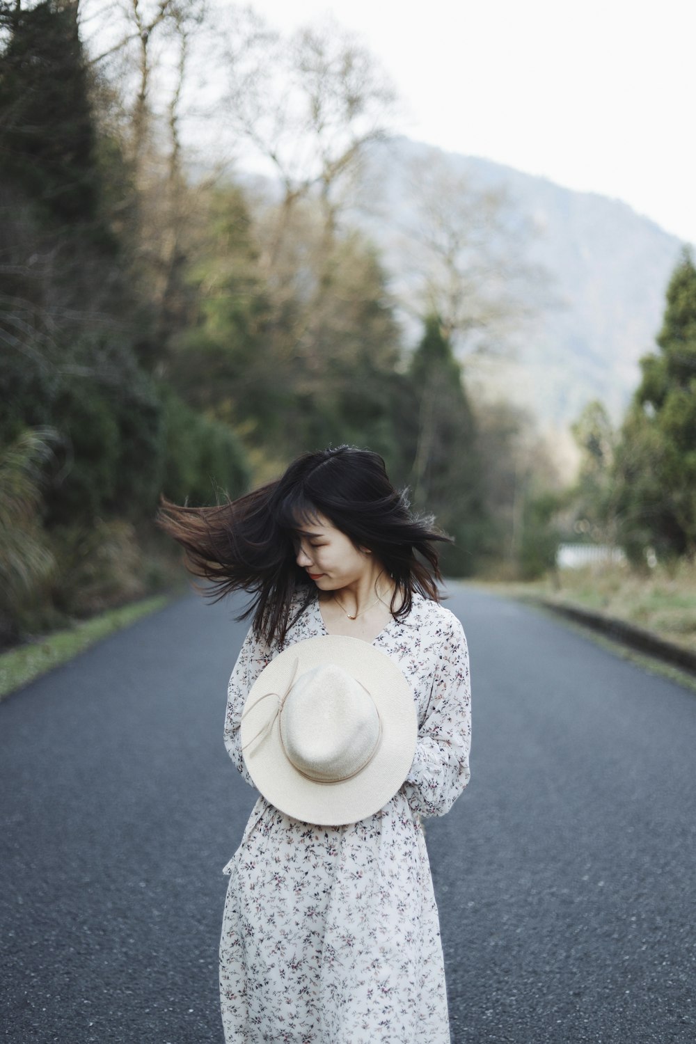 woman holding her white hat outdoort