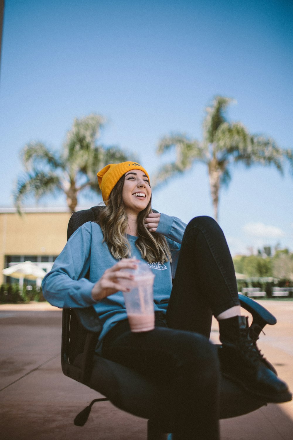 woman sitting on rolling armchair holding fruit shake