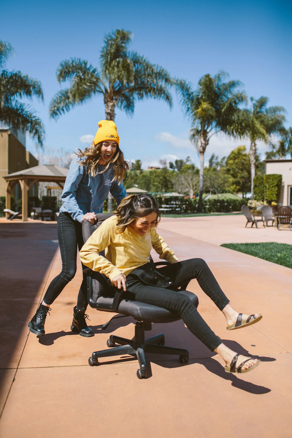 two smiling women sitting on rolling chair