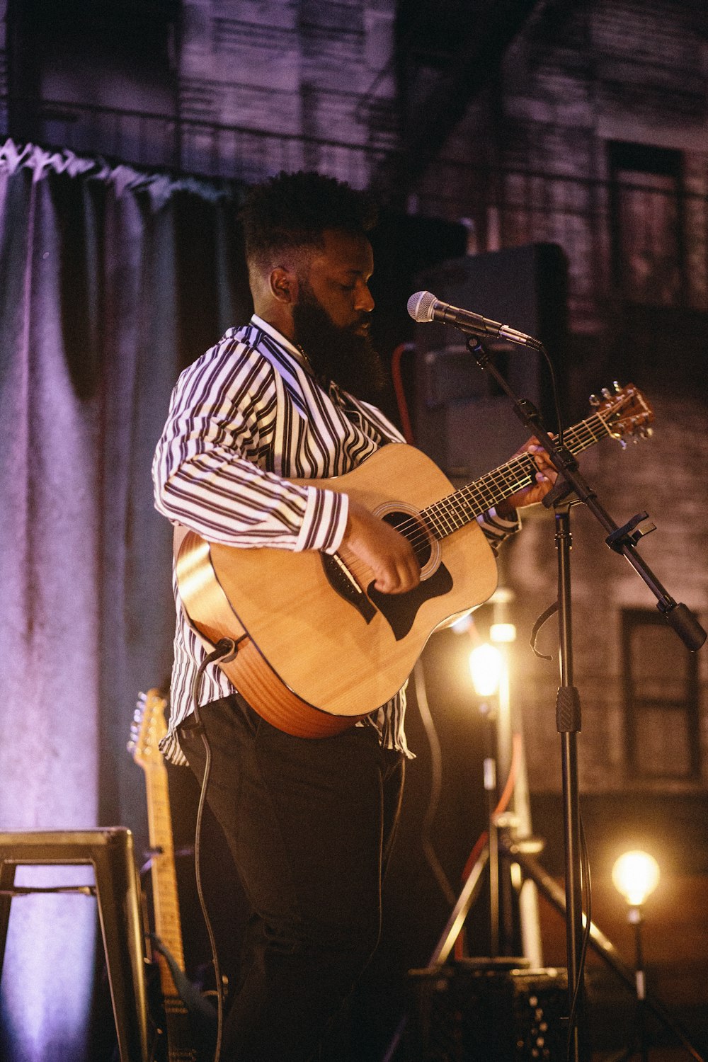 man holding guitar beside microphone with stand