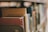Books on a shelf with a focus on the spine of a red hardcover book, surrounded by other books with varying colors, in a library or study setting.