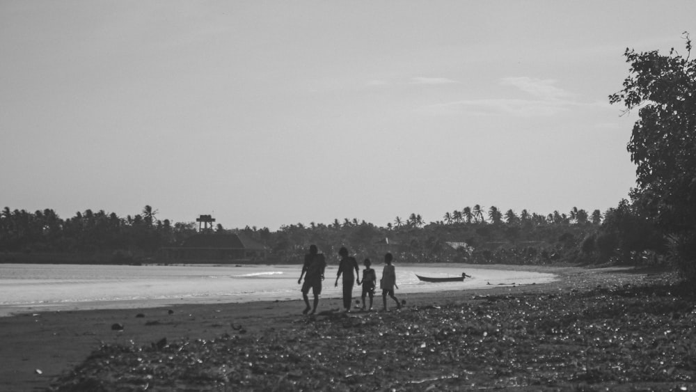 four person walking on shore near trees