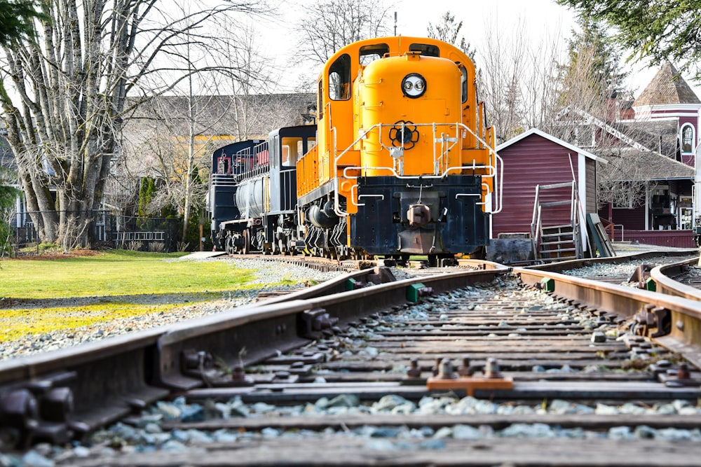 train on railroad near trees and buildings