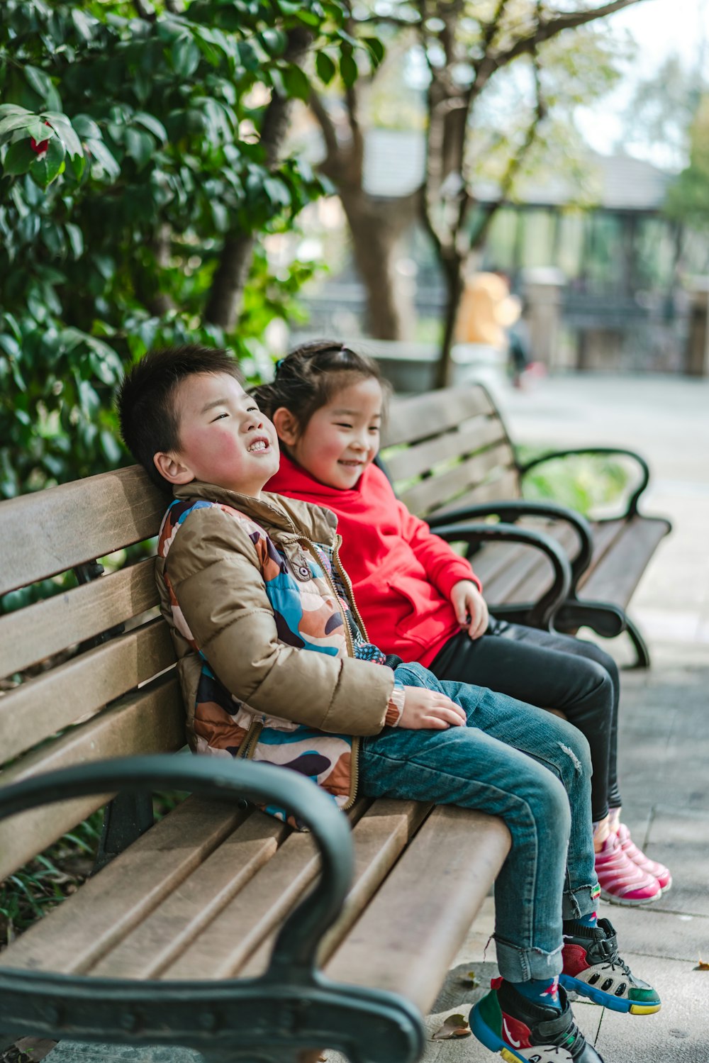 2 kids sitting on bench during daytime