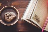 A close-up of a steaming cup of coffee beside an open notebook filled with creative ideas.