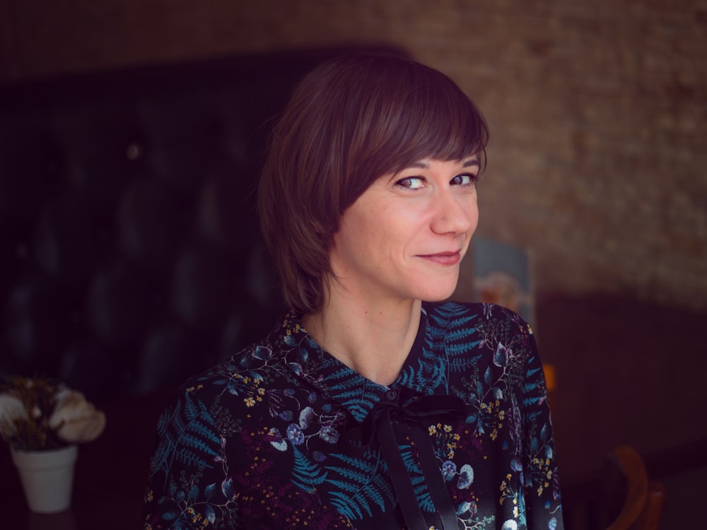 smiling woman wearing black and green floral collared shirt