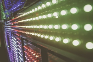 Rows of colorful LED lights are arranged in a parallel pattern, creating a vibrant and dynamic visual effect. The lights appear to extend into the distance, with a blend of green, red, and blue hues. The image captures the glow and reflection of the lights, giving it a futuristic and abstract feel.