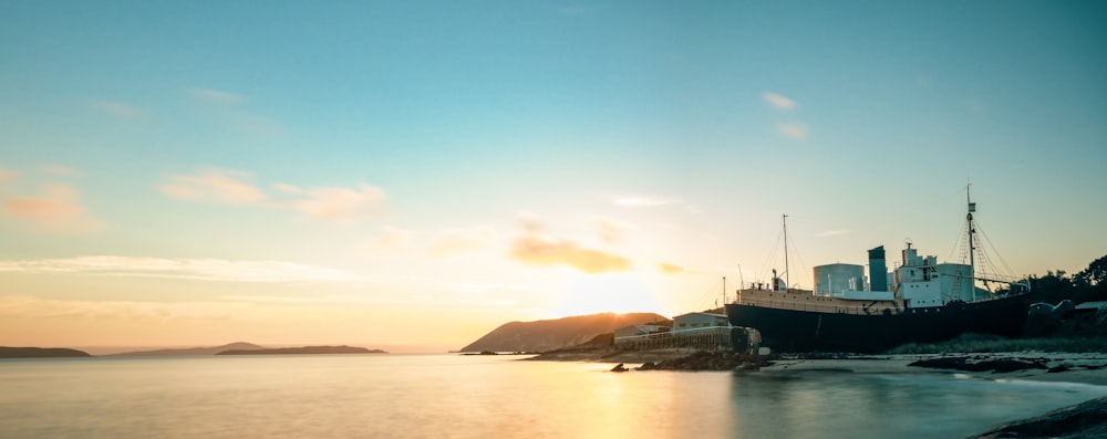 ship on dock near hill during sunrise